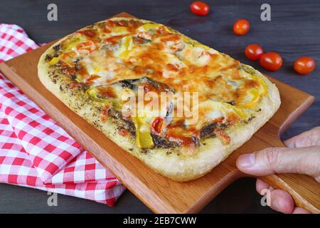 Hand platzieren köstliche frisch gebackene hausgemachte Pesto Veggie Pizza auf Die Tabelle Stockfoto