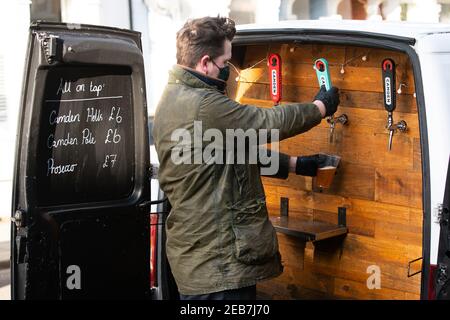 George Dean, ein ehemaliger Barmanager, gießt ein Bier mit seinem "Pub-on-wheels" in Clapham, Süd-London. George und Finn fahren zu den Türen der Leute, um ihnen Pints zu schenken und schaffen mehr ein Pub-Erlebnis als Dosen in ihren Wohnzimmern. Bilddatum: Freitag, 12. Februar 2021. Stockfoto