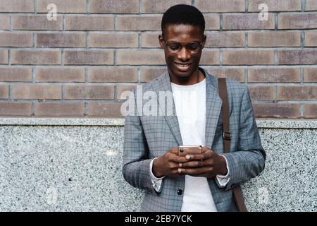 Glücklicher afroamerikanischer Mann mit Handy, während er stand City Street Stockfoto
