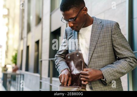 Gut aussehend smart afrikanischen Mann tragen Anzug mit Laptop-Computer, während In der Straße stehen Stockfoto