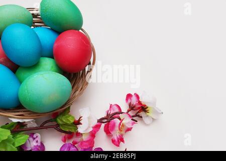 Bunte Ostereier und Brunch mit Blumen auf weißem Hintergrund Stockfoto