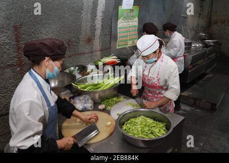 (210212) -- JINCHANG, 12. Februar 2021 (Xinhua) -- Logistisches Personal kocht Abendessen für Bergleute in der dritten Bergbauzone der Jinchuan Gruppe in Jinchang, nordwestlich von Chinas Provinz Gansu, 11. Februar 2021. In der dunklen Mine in einer Tiefe von mehr als 600 Metern brüllen die Bergbaumaschinen und das Erz auf dem Förderband erstrahlt in metallischem Glanz. Es ist die dritte Bergbauzone der Jinchuan-Gruppe in Jinchang, einer der wichtigsten Produktionsstandorte des Landes für Nickel, Kobalt und Kupfer. Arbeiter hier, die während des Frühlingsfestes nicht nach Hause zurückkamen, blieben an ihren Posten, um den Minenbetrieb in einem Auftrag zu gewährleisten Stockfoto