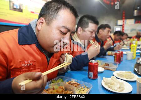 (210212) -- JINCHANG, 12. Februar 2021 (Xinhua) -- Bergmänner essen am Vorabend des Mondneujahres in der dritten Bergbauzone der Jinchuan Gruppe in Jinchang, nordwestlich von Chinas Provinz Gansu, 11. Februar 2021. In der dunklen Mine in einer Tiefe von mehr als 600 Metern brüllen die Bergbaumaschinen und das Erz auf dem Förderband erstrahlt in metallischem Glanz. Es ist die dritte Bergbauzone der Jinchuan-Gruppe in Jinchang, einer der wichtigsten Produktionsstandorte des Landes für Nickel, Kobalt und Kupfer. Arbeiter hier, die während des Frühlingsfestes nicht nach Hause zurückkamen, blieben an ihren Posten, um die Minenoperati zu gewährleisten Stockfoto