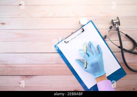 Arzt Hand in Latexhandschuhe schreiben Rezept auf Schreibtisch, Draufsicht Stockfoto