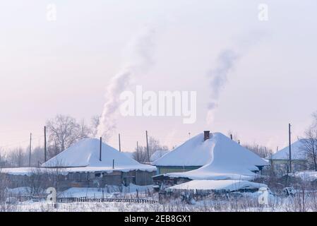 Russisches Dorf mit altem Holztraditonellen russischen Stil. Die Dächer sind während des frostigen Wintertages von Schnee bedeckt. Stockfoto