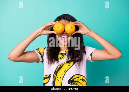 Foto von jungen Mädchen halten zwei Orangen schließen Augen offen Mund tragen Banana Print T-Shirt isoliert türkis Farbe Hintergrund Stockfoto