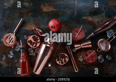 Alkoholische Getränke oder Cocktails Hintergrund mit Bar und Pub Utensilien, serviert Gläser Cocktail auf den Felsen , Granatapfel um ein Kupfer verstreut Stockfoto