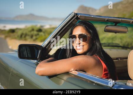 Gemischte Rennen Frau fahren an sonnigen Tag im Cabrio-Auto Halten Sie das Lenkrad und lächeln Sie Stockfoto