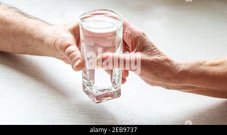 Oma gibt Großvater ein Glas Wasser. Selektiver Fokus. Essen. Stockfoto