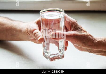 Oma gibt Großvater ein Glas Wasser. Selektiver Fokus. Essen. Stockfoto