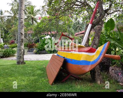 Ein traditionelles Boot namens Jukung wurde auf das Gras des Senggigi Beach, Lombok, Indonesien gelegt Stockfoto