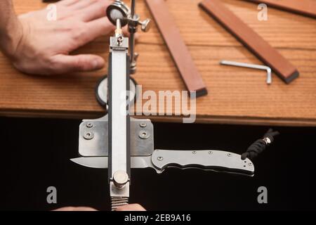 Mann mit einer manuellen Maschine, um ein Taschenmesser zu schärfen Stockfoto