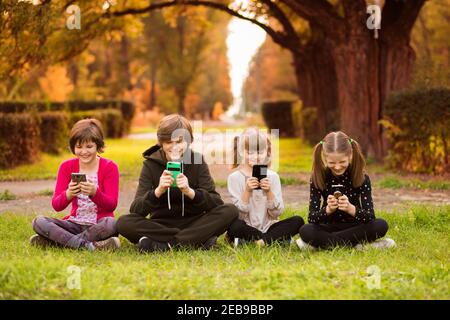 Smartphone sucht Gruppe von kleinen Kindern beobachten Film Cartoon zusammen auf digitalen Tablet. Kinder spielen mit dem Telefon zusammen Stockfoto