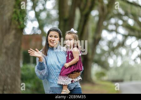 Eine Mutter, die ihre junge Tochter hält und etwas erklärt. Stockfoto