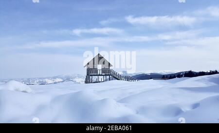 Kleines Holzhaus auf einem schneebedeckten Feld, das in Kulakkaya Plateau, Giresun, Türkei gefangen wurde Stockfoto