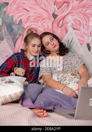 Russland, Moskau, Februar 2021. Zwei Mädchen im Teenageralter auf einem zerlegten Bett im bunten Schlafanzug.Freundinnen zu Hause. Stockfoto