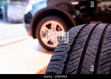 Nahaufnahme eines alten Reifens mit Hintergrund des Autorades. Reifenwerkstatt und altes Rad am Auto wechseln. Gebrauchte Autoreifen, die bei der Reifenmontage in Stapeln gestapelt werden Stockfoto