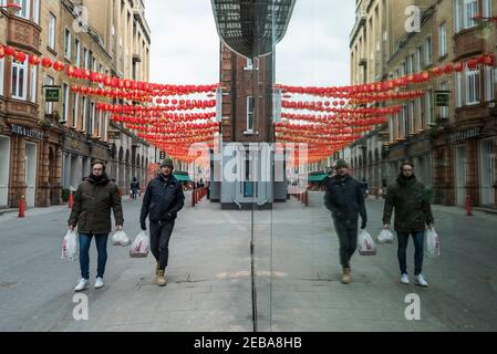 London, Großbritannien. 12. Februar 2021. Einkäufer nach einem Besuch im Loon Fung Supermarkt, während rote Laternen über dem Chinatown der Hauptstadt am chinesischen Neujahr, dem Jahr des Ochsen, hängen. Aufgrund der anhaltenden Coronavirus-Pandemie bleibt die Gegend ruhig. Mit Sperrbeschränkungen wird es keine formellen Feiern geben. Stattdessen werden Veranstalter Veranstaltungen online ausrichten. Kredit: Stephen Chung / Alamy Live Nachrichten Stockfoto