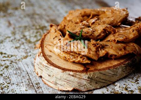 Nahaufnahme von einigen gewürzten und gekochten imitierten Hähnchenfleischstreifen auf einem Holztablett serviert, auf einem rustikalen Holztisch platziert Stockfoto