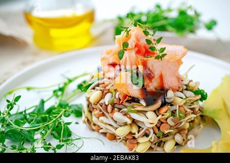 Salat aus gekeimtem Bohnen, Getreide und Micro-Greens mit Scheiben von rotem Fisch und Fischsoße, Sojabohnen mit Tamarindensoße und Scheiben Avocado. Niedrig-c Stockfoto