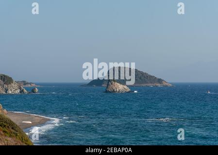 Eine Insel in der Mitte des Meeres mit grüner Vegetation und einem kleinen Felsen davor bedeckt. Stockfoto