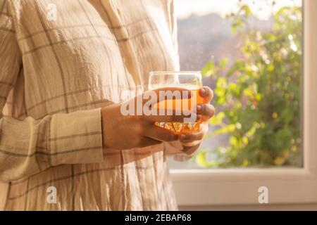 Eine junge Frau trinkt einen frisch und lecker gepressten Orangensaft, gesund und voller Vitamine, am Morgen, zu Hause, vor dem Frühstück und Stockfoto