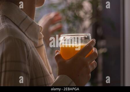 Eine junge Frau trinkt einen frisch und lecker gepressten Orangensaft, gesund und voller Vitamine, am Morgen, zu Hause, vor dem Frühstück und Stockfoto