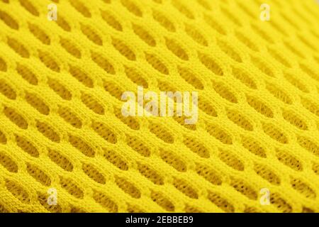 Fragment einer perforierten Zehe eines gelben Sneakers in Nahaufnahme. Texturierte Textur des Materials von Sportschuhen. Stockfoto