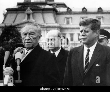 Ankunftszeremonie für Konrad Adenauer, Bundeskanzler der Bundesrepublik Deutschland, 10:45am Uhr. Präsident John F. Kennedy sieht sich als Bundeskanzler der Bundesrepublik Deutschland, Dr. Konrad Adenauer, hält Bemerkungen während der Ankunftszeremonie zu seinen Ehren. US-Außenminister Dean Rusk steht im Zentrum. Im Hintergrund ist das Executive Office Building zu sehen. South Lawn, White House, Washington, D.C. Stockfoto