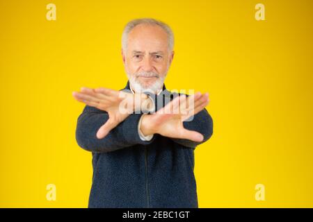 Grau bärtige Haare Senior über gelben Hintergrund Ablehnung Ausdruck Kreuzung Arme und Handflächen tun negative Zeichen Stockfoto