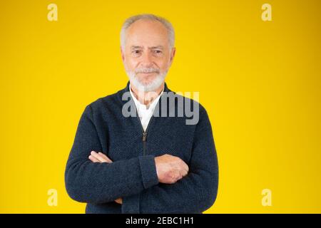 Lächelndes Gesicht eines gutaussehenden älteren bärtigen Mannes mit blauer Jacke Isoliert auf gelbem Hintergrund Stockfoto