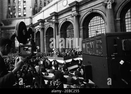 Kongreßfeldzug Reise: Cleveland, Ohio, Ankunft, Rallye, Autokolonne, Abfahrt. Präsident John F. Kennedy (auf der Plattform) hält während einer Wahlkampfreise im Kongress auf dem Public Square in Cleveland, Ohio, eine Rede. Im Vordergrund arbeitet ein Kamerabediener. Stockfoto