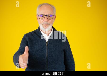 Ein älterer Mann, der auf einem weißen Hintergrund stand und freundlich lächelte und Handschlag als Begrüßung und Begrüßung anbot. Erfolgreiches Geschäft. Stockfoto