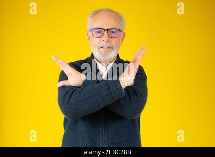 Grau bärtige Haare Senior über gelben Hintergrund Ablehnung Ausdruck Kreuzung Arme und Handflächen tun negative Zeichen Stockfoto