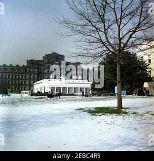 First Lady Jacqueline Kennedyu0027s (JBK) Schlittenfahrt auf dem South Lawn. First Lady Jacqueline Kennedy und unbekannte Kinder nähern sich in einem offenen Schlitten, der von Caroline Kennedyu0027s Pony Macaroni gezogen wird, dem Südeingang des Weißen Hauses; mehrere wartende Kinder stehen in der Nähe. Der Westflügel und das Executive Office Building sind im Hintergrund zu sehen. South Lawn, Washington, D.C. Stockfoto