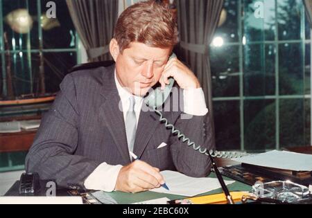 Telefonanschrift an die American Veterans (AMVETS) Convention in New York City, 12:00pm Uhr. Präsident John F. Kennedy (am Schreibtisch sitzend) hält telefonische Bemerkungen an die American Veterans of World war II (AMVETS) Convention in New York, New York. Oval Office, White House, Washington, D.C. Stockfoto
