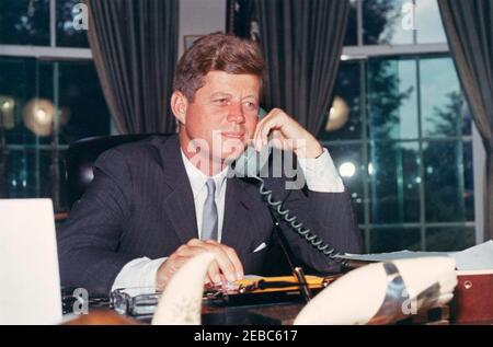 Telefonanschrift an die American Veterans (AMVETS) Convention in New York City, 12:00pm Uhr. Präsident John F. Kennedy (am Schreibtisch sitzend) hält telefonische Bemerkungen an die American Veterans of World war II (AMVETS) Convention in New York, New York. Oval Office, White House, Washington, D.C. Stockfoto