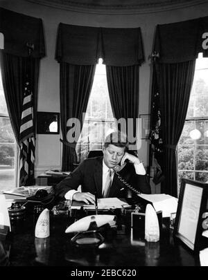 Telefonanschrift an die American Veterans (AMVETS) Convention in New York City, 12:00pm Uhr. Präsident John F. Kennedy (am Schreibtisch sitzend) hält telefonische Bemerkungen an die American Veterans of World war II (AMVETS) Convention in New York, New York. Oval Office, White House, Washington, D.C. Stockfoto