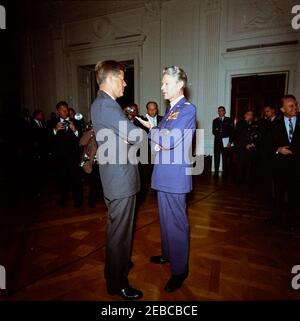 Verleihung der Distinguished Service Medal (DSM) an General Lauris Norstad, 12:45pm. Präsident John F. Kennedy (Mitte links) besucht den pensionierten Oberbefehlshaber der NATO, General Lauris Norstad, nachdem er ihm die Distinguished Service Medal überreichen hatte. Ebenfalls abgebildet, im Hintergrund stehend mit anderen Gästen: Fotograf des Weißen Hauses, Captain Cecil Stoughton; Newsreel-Fotograf für United Press Movieton, Thomas J. Craven, Sr. East Room, White House, Washington, D.C. Stockfoto