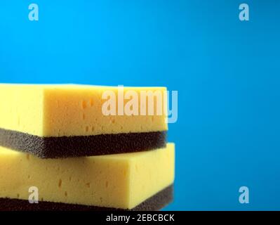 Stapel von Gelb mit schwarzen Scheuerschwämme Schwämme mit luftigen blauen Hintergrund kombiniert. Haushalt, Fahrzeuge oder Reinigungskonzepte. Stockfoto