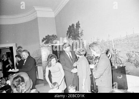 Geburtstagsfeier für Caroline Kennedy und John F. Kennedy, Jr.. Präsident John F. Kennedy schüttelt sich bei einer gemeinsamen Geburtstagsfeier für Caroline Kennedy und John F. Kennedy, Jr. die Hände mit einer unbekannten Frau; First Lady Jacqueline Kennedy (Mitte links) steht hinter ihrem Sohn John, Jr. auch im Bild: Erste Sozialsekretärin Ladyu0027s, Letitia Baldrige; Butler des Weißen Hauses, John W. Ficklin. Presidentu2019s Esszimmer (Residenz), Weißes Haus, Washington, D.C. [Flecken auf der linken Seite des Bildes sind original auf das Negative.] Stockfoto