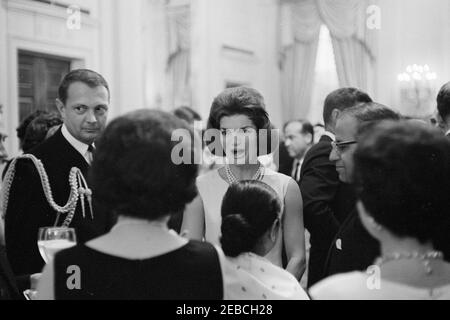 Diplomatischer Empfang, 6:00pm Uhr. First Lady Jacqueline Kennedy (Mitte) besucht mit Gästen im East Room während eines diplomatischen Empfangs im Weißen Haus, Washington, D.C. Naval Aide to the President, Captain Tazewell Shepard, steht auf der linken Seite; Botschafterin von Nepal, Matrika Prasad Koirala, steht auf der rechten Seite (mit Brille); Präsident John F. Kennedy steht hinter Botschafter Koirala (Gesicht versteckt). Stockfoto