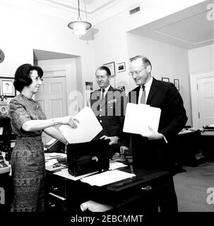 Mitarbeiter des Weißen Hauses: Militärhilfe für den Präsidenten Gen. Chester V. Clifton, nationaler Sicherheitsberater McGeorge Bundy, Präsidialsekretärin Evelyn Lincoln. Persönliche Sekretärin von Präsident John F. Kennedy Evelyn Lincoln (links) legt einen Aktenordner in Präsident Kennedyu0027s schwarz Alligator Aktentasche als Sonderassistent des Präsidenten für nationale Sicherheitsangelegenheiten McGeorge Bundy hält die Aktentasche offen. Military Aide to the President General Chester V. Clifton (Mitte) schaut auf. Büro Presidentu2019s Secretaryu2019s, Weißes Haus, Washington, D.C. Stockfoto