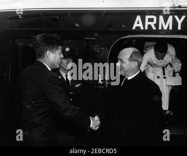 Begrüßungszeremonie nach der Rückkehr der US-Delegation zur Konferenz von Punta del Este, 2:10pm Uhr. Präsident John F. Kennedy begrüßt Staatssekretär Dean Rusk als Sekretär Rusk und andere Delegierte kehren von der Punta del Este Konferenz in Uruguay zurück. Sekretärin Rusku2019s Frau Virginia Rusk verlässt den Hubschrauber der United States Army; ein nicht identifiziertes Mitglied des Militärs schaut zu. Fallender Schnee ist sichtbar. South Lawn, White House, Washington, D.C. Stockfoto