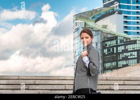 Attraktive Frau, die gerade auf städtischen Hintergrund. Weiblich auf Stadtbild Hintergrund mit bewölktem Himmel für Copy Space. Entschlossene und erfolgreiche Frau Stockfoto