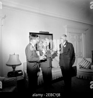 Reise nach Bermuda: Generalmajor Sir Julian Gascoigne, Gouverneur von Bermuda, überreicht Geschenke an Präsident Kennedy und Harold Macmillan, Premierminister von Großbritannien, im Government House, Hamilton, Bermuda. Präsident John F. Kennedy und Premierminister von Großbritannien Harold Macmillan (Mitte) erhalten Porzellanfiguren vom Gouverneur von Bermuda, Generalmajor Sir Julian Gascoigne (rechts), im Government House in Hamilton, Bermuda. President Kennedyu2019s Figur zeigt einen spanischen Hog-Fisch und einen Sergeant Major Fisch, der um ein Stück Koralle schwimmt; eine silberne Plakette auf der Basis lautet: u0022The Stockfoto