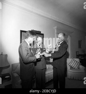 Reise nach Bermuda: Generalmajor Sir Julian Gascoigne, Gouverneur von Bermuda, überreicht Geschenke an Präsident Kennedy und Harold Macmillan, Premierminister von Großbritannien, im Government House, Hamilton, Bermuda. Präsident John F. Kennedy und Premierminister von Großbritannien Harold Macmillan (Mitte) erhalten Porzellanfiguren vom Gouverneur von Bermuda, Generalmajor Sir Julian Gascoigne (rechts), im Government House in Hamilton, Bermuda. President Kennedyu2019s Figur zeigt einen spanischen Hog-Fisch und einen Sergeant Major Fisch, der um ein Stück Koralle schwimmt; eine silberne Plakette auf der Basis lautet: u0022The Stockfoto