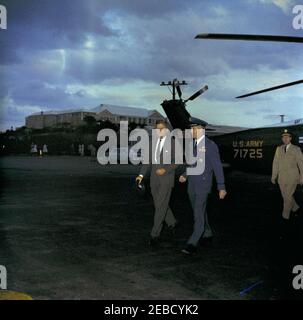 Reise nach Bermuda: Abfahrt vom Luftwaffenstützpunkt Kindley, Bermuda, 5:30pm Uhr. Präsident John F. Kennedy (mit Hut) geht vor seiner Abreise aus Bermuda von Marine One zur Air Force One; der Präsident besuchte Bermuda, um an Treffen mit dem britischen Premierminister Harold Macmillan teilzunehmen. Ein nicht identifizierter Militäroffizier geht mit Präsident Kennedy; Militärhilfe zum Präsidenten General Chester V. Clifton läuft ganz rechts vor dem Hubschrauber. Kindley Air Force Base, St. Davidu2019s Island, Bermuda. Stockfoto