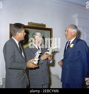 Reise nach Bermuda: Generalmajor Sir Julian Gascoigne, Gouverneur von Bermuda, überreicht Geschenke an Präsident Kennedy und Harold Macmillan, Premierminister von Großbritannien, im Government House, Hamilton, Bermuda. Präsident John F. Kennedy und Premierminister von Großbritannien Harold Macmillan (Mitte) erhalten Porzellanfiguren vom Gouverneur von Bermuda, Generalmajor Sir Julian Gascoigne (rechts), im Government House in Hamilton, Bermuda. President Kennedyu2019s Figur zeigt einen spanischen Hog-Fisch und einen Sergeant Major Fisch, der um ein Stück Koralle schwimmt; eine silberne Plakette auf der Basis lautet: u0022The Stockfoto