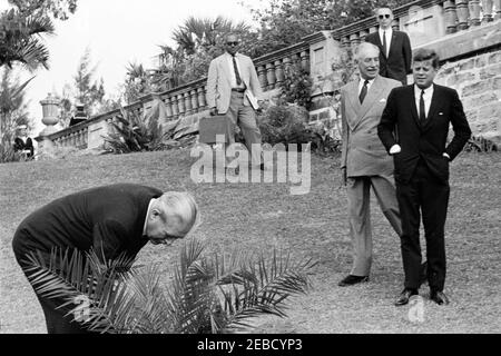 Ausflug nach Bermuda: Baumpflanzung im Government House, Hamilton, Bermuda. Premierminister von Großbritannien Harold Macmillan schneidet ein Band von einem neu gepflanzten Baum auf dem Gelände des Government House in Hamilton, Bermuda. L-R: Premierminister Macmillan; Associate White House Press Secretary Andrew T. Hatcher; Gouverneur von Bermuda Major General Sir Julian Gascoigne; White House Secret Service Agent Ernest u201cErnieu201d Olsson (im Rücken); Präsident John F. Kennedy. Stockfoto